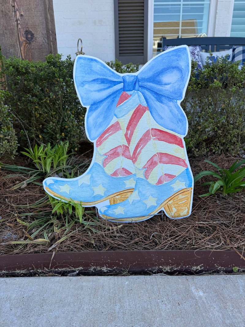 Decorative boot with a blue bow, featuring American flag design, on a grassy area.
