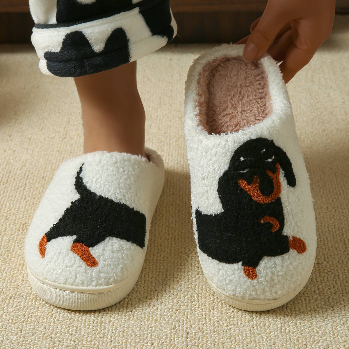 White slippers with black dog design on a beige carpet