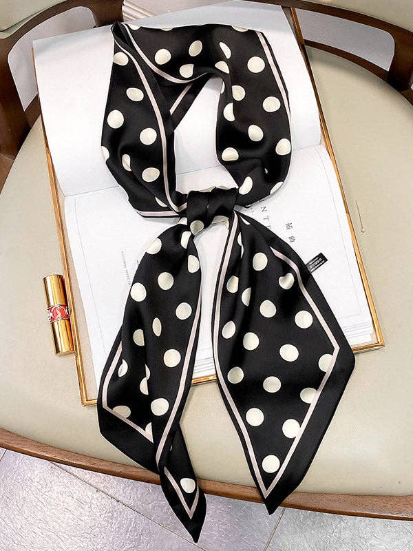 Black and white polka dot scarf on an open book with a gold lipstick.