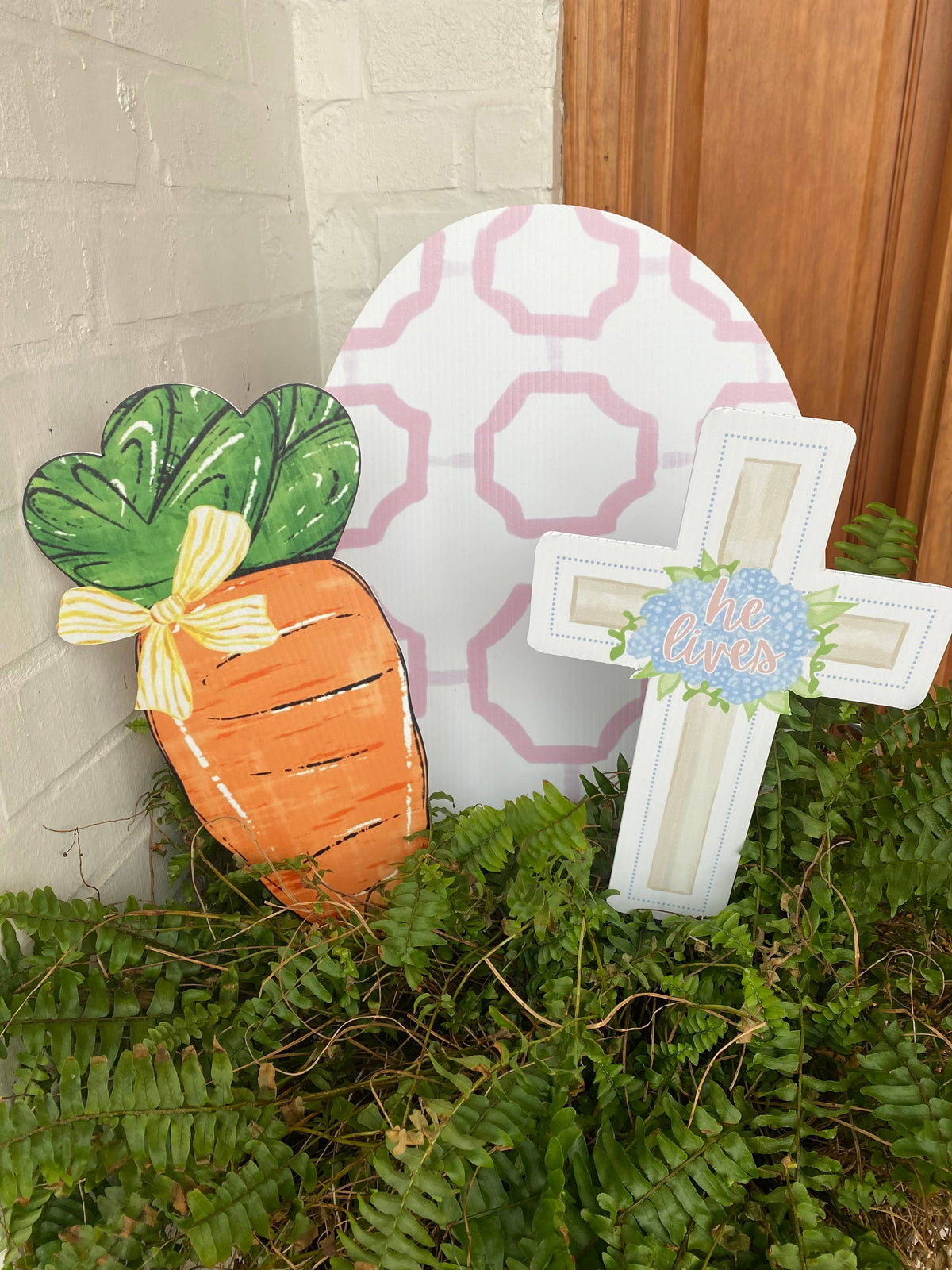 Decorative Easter egg with a carrot and cross, placed outdoors on a stone surface.