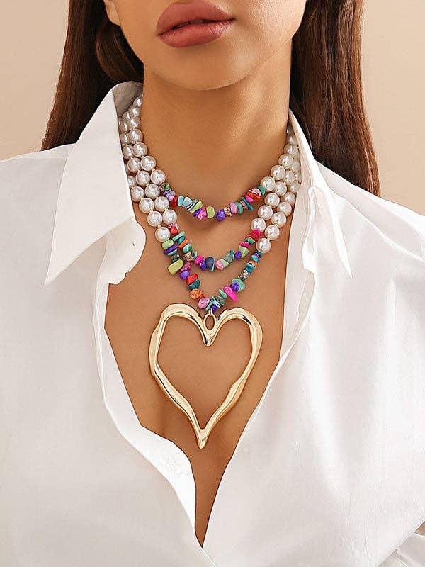 Close-up of a woman wearing a colorful beaded necklace with a gold heart pendant.