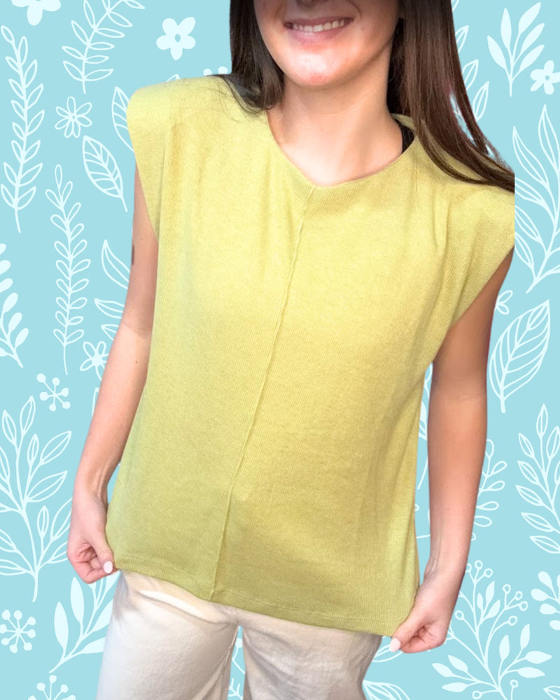 Woman wearing a light green sleeveless top against a blue background with white leaf patterns