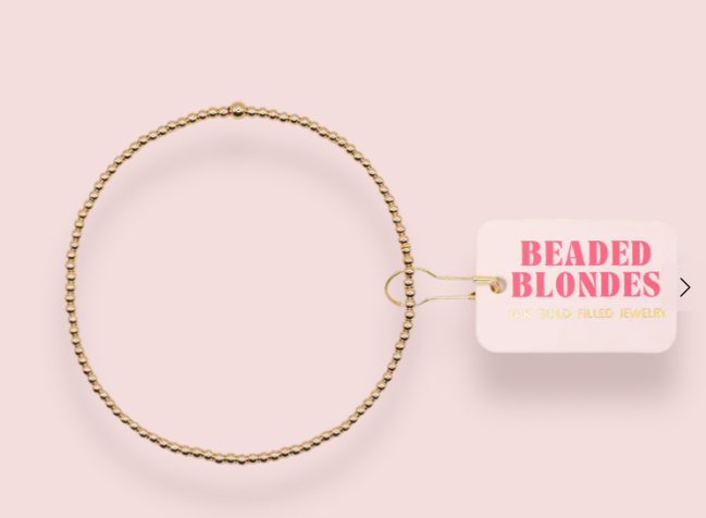 Gold beaded hair ring with a 'Beaded Blondes' tag on a pink background