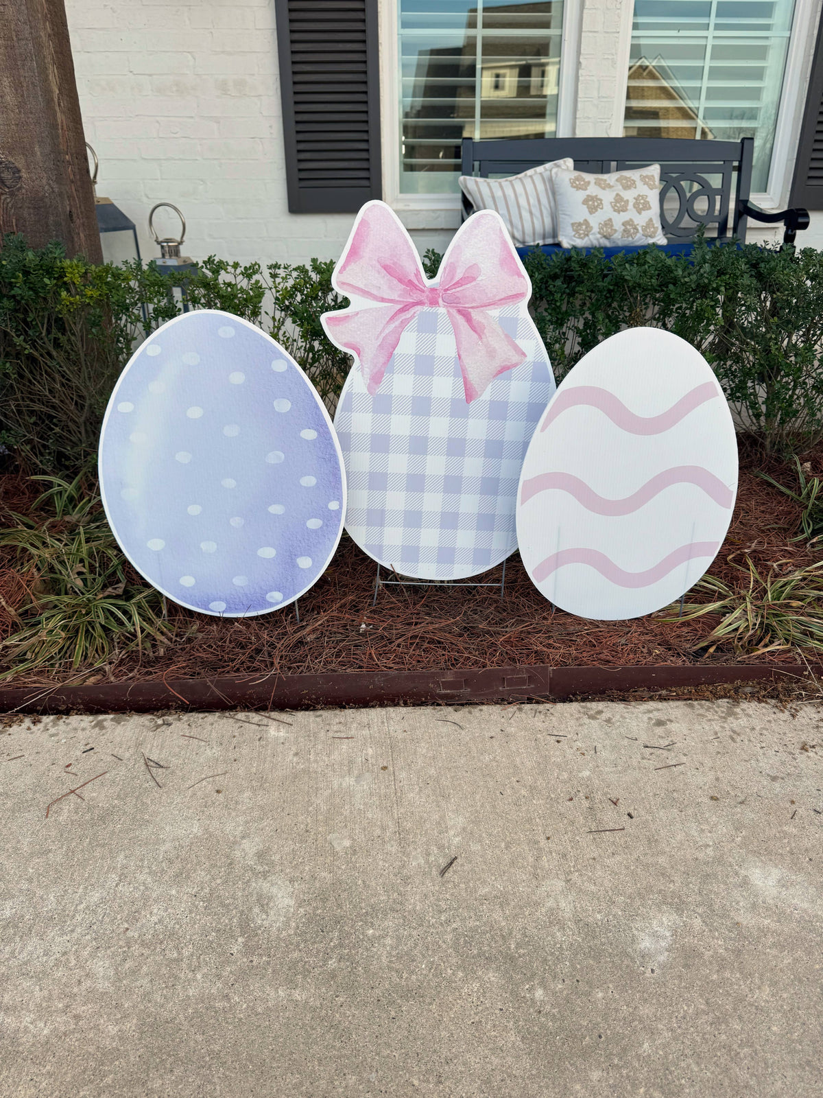 Decorative Easter eggs with polka dots, plaid pattern, and wavy design on a sidewalk.