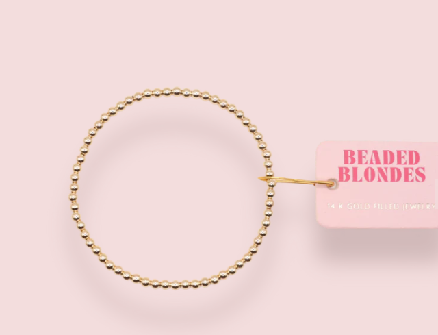 Gold beaded hair tie on a pink background with 'Beaded Blondes' branding.