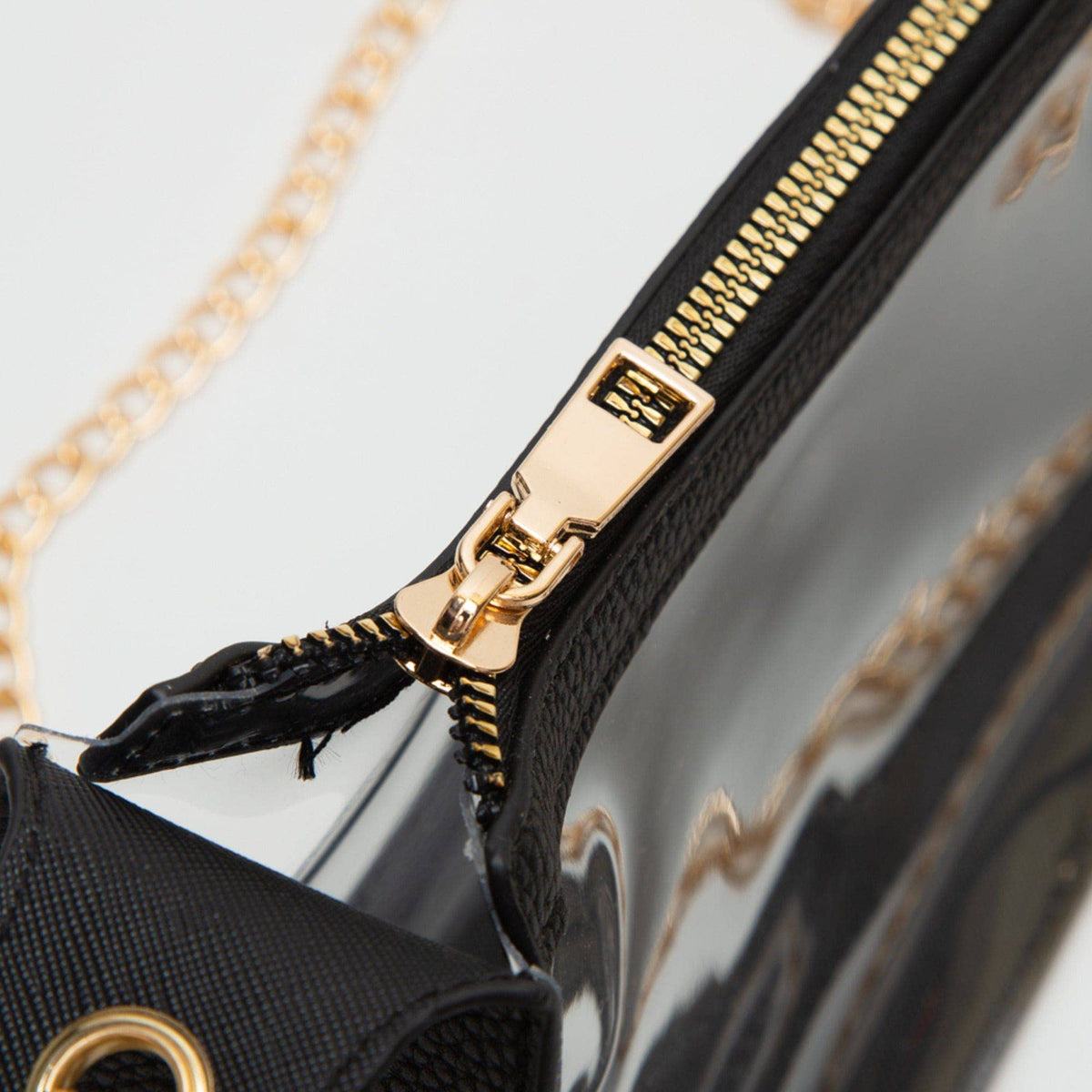 Close-up of a black handbag with gold zipper and chain detail.