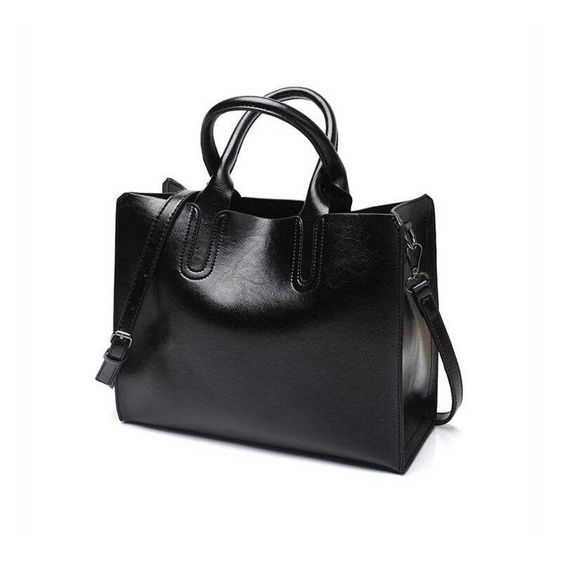 A black leather tote bag with dual top handles and a detachable shoulder strap, photographed on a clean white background.