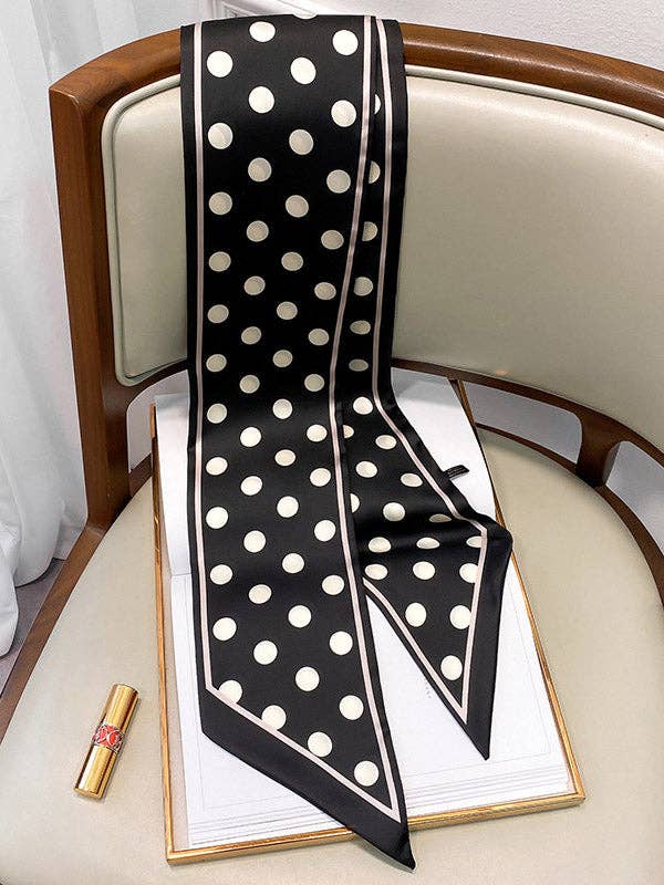 Black and white polka dot scarf on a chair with a box and lipstick beside it.