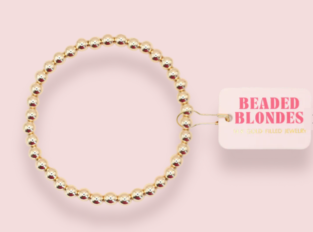 Gold beaded bracelet on a pink background with 'Beaded Blondes' branding.