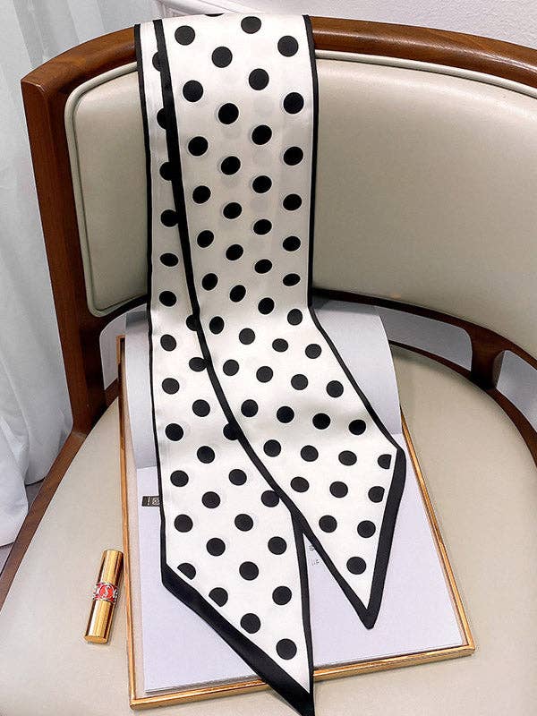 Black and white polka dot scarf on a chair with a box and lipstick.