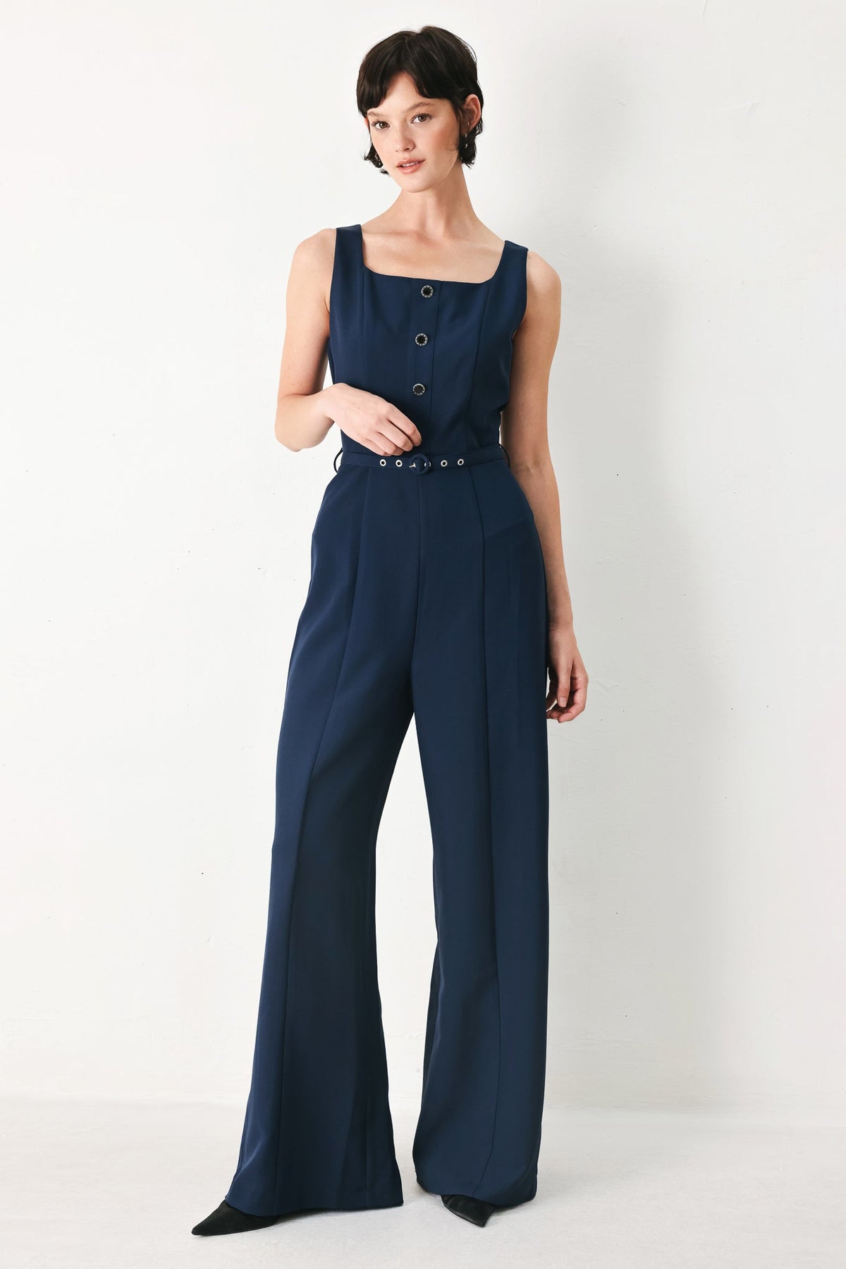 Woman wearing a navy blue jumpsuit on a white background