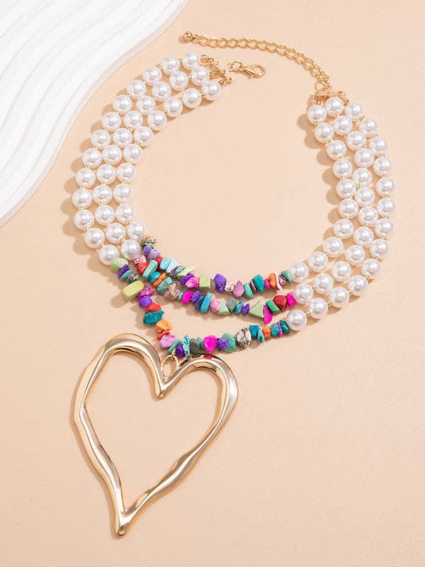 Necklace with pearl and multicolored bead strands and a gold heart pendant on a beige background