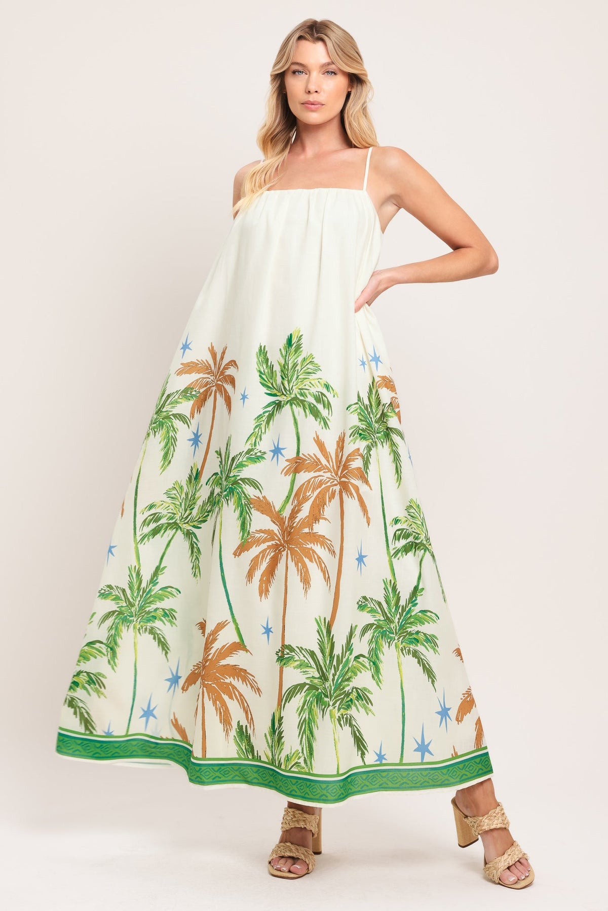 Woman wearing a white dress with palm tree pattern on a plain background