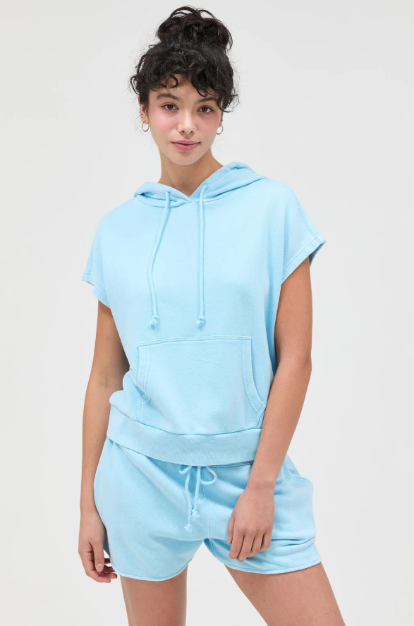 Person wearing a light blue hoodie and shorts set on a plain background