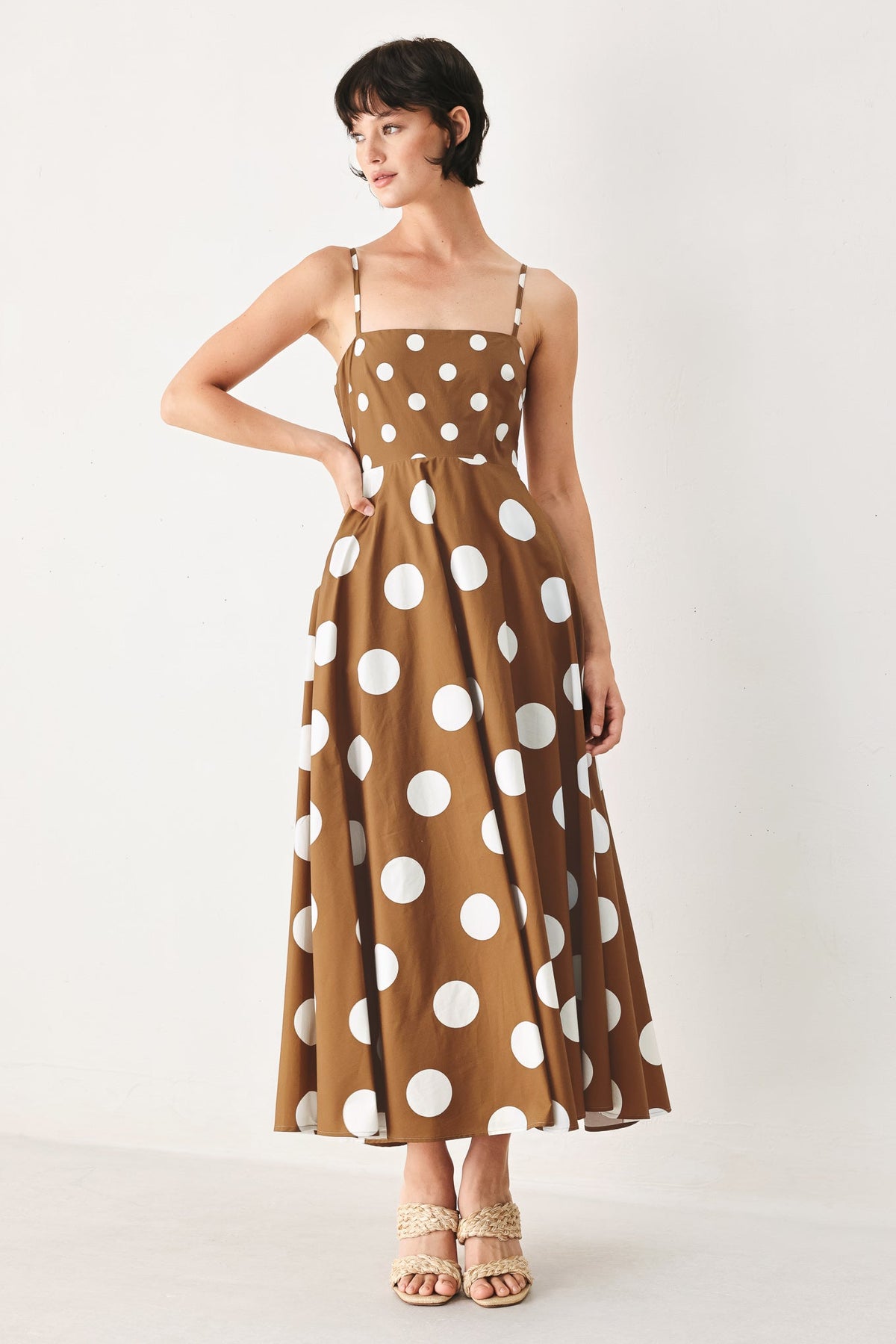 Woman wearing a brown dress with white polka dots on a white background