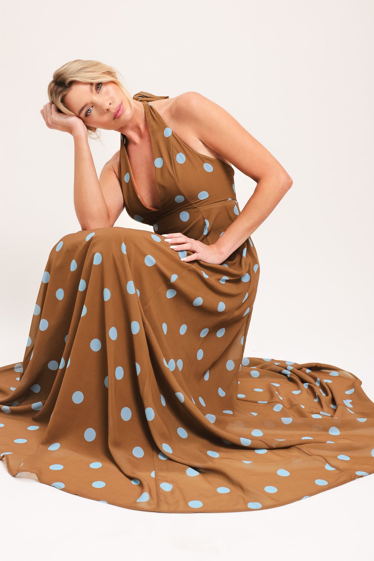 Woman wearing a brown dress with white polka dots on a white background