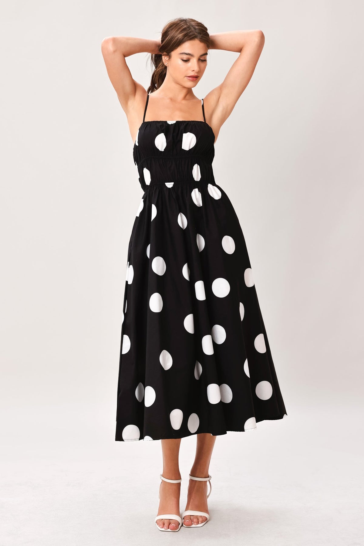 Woman wearing a black dress with white polka dots on a white background