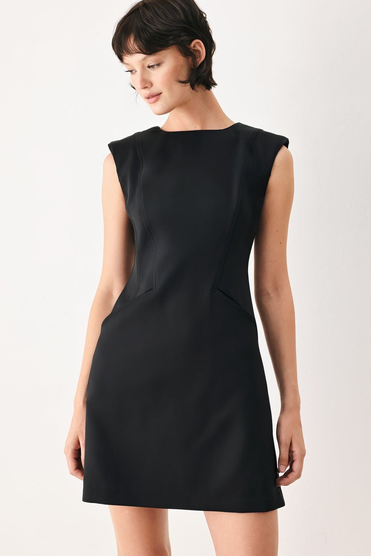 Woman wearing a black sleeveless dress against a white background