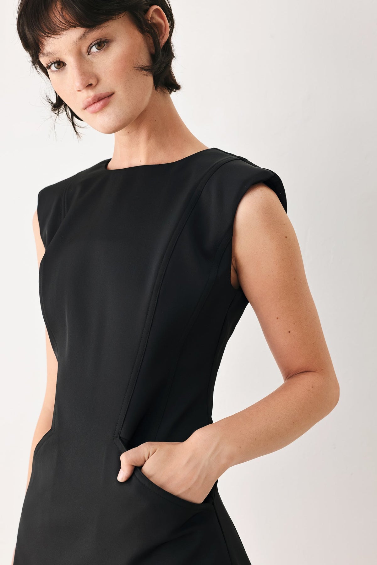 Woman wearing a black sleeveless dress against a white background