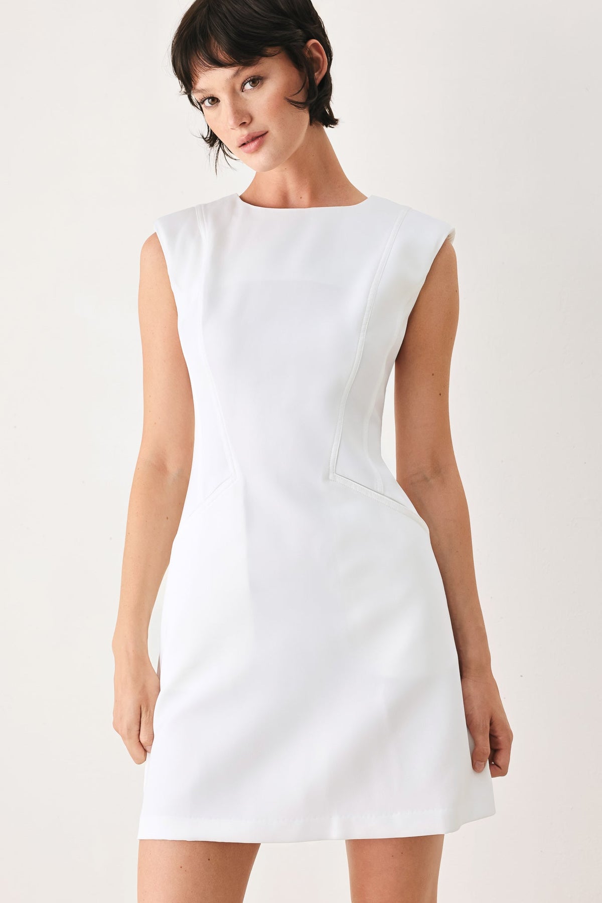 Woman wearing a white sleeveless dress on a plain background