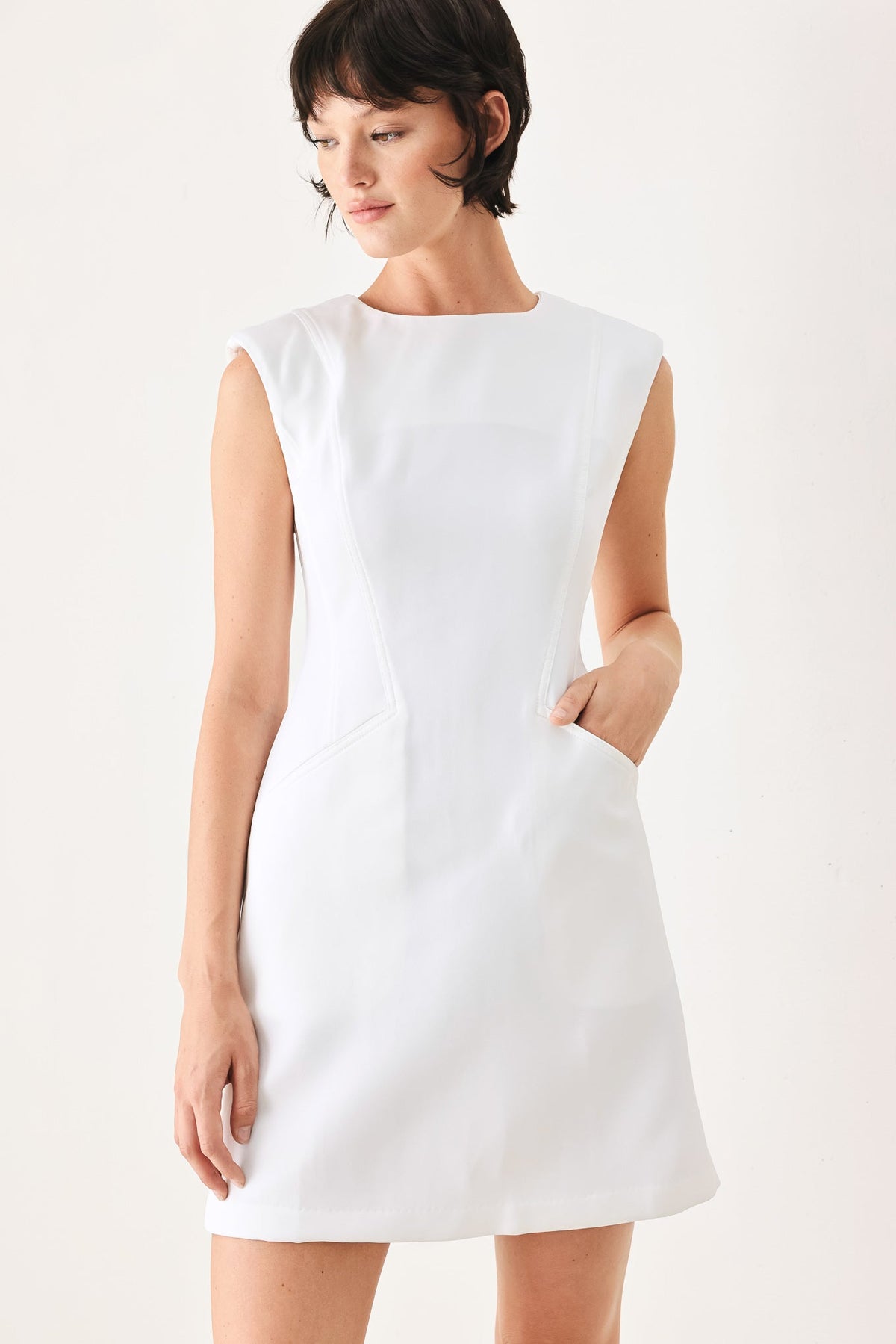 Woman wearing a white sleeveless dress on a plain background