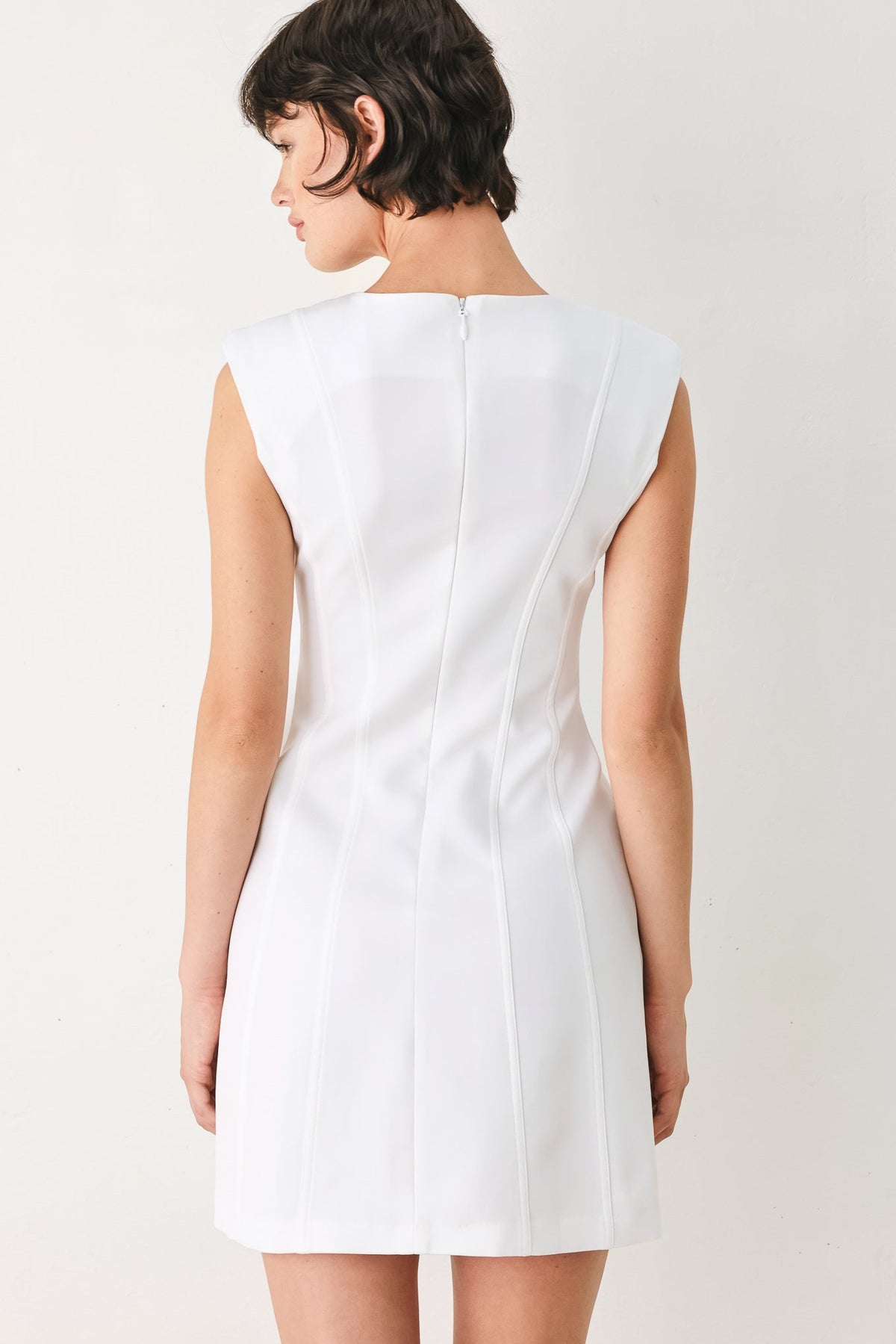 White sleeveless dress worn by a person on a plain background
