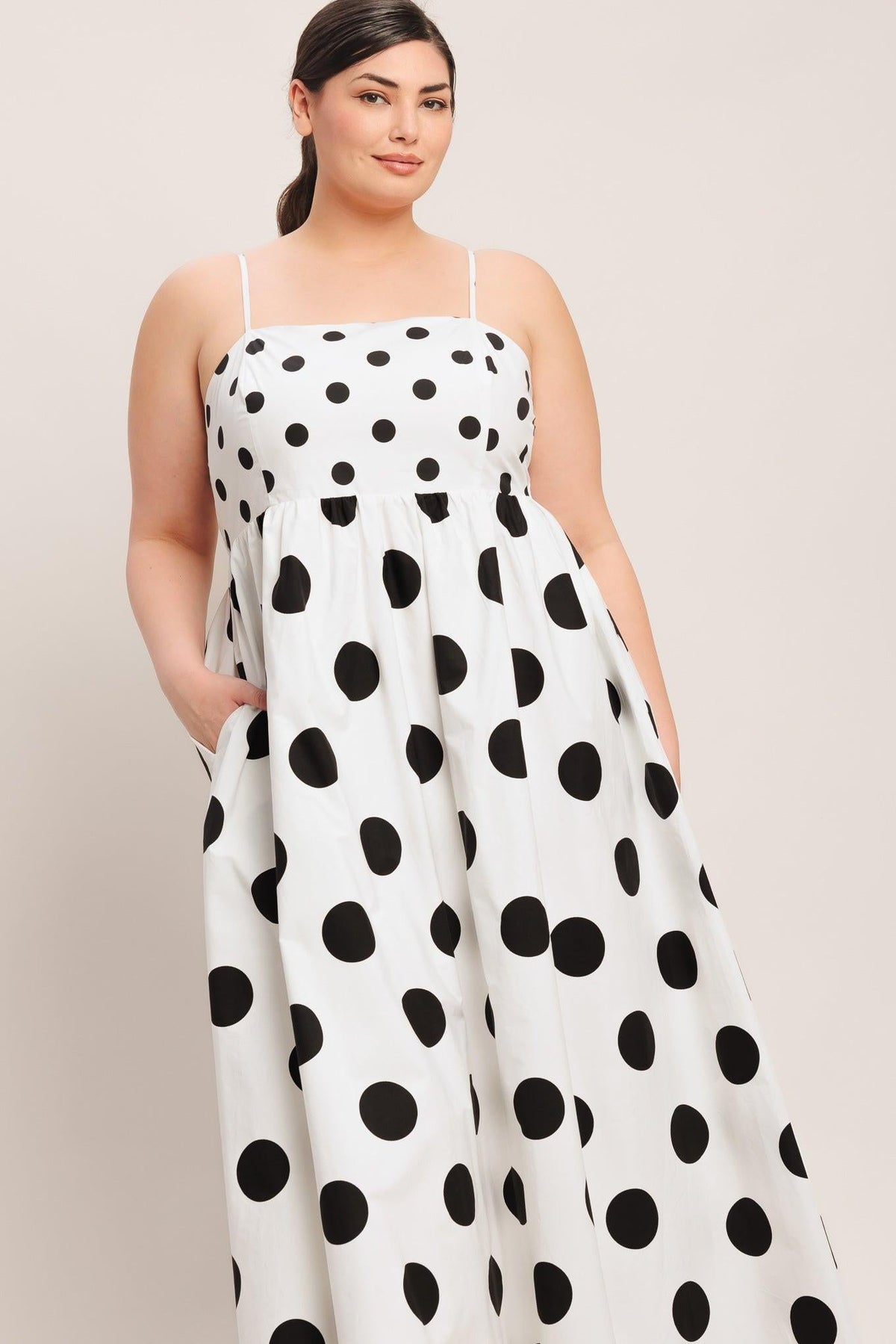 Woman wearing a white dress with black polka dots against a plain background