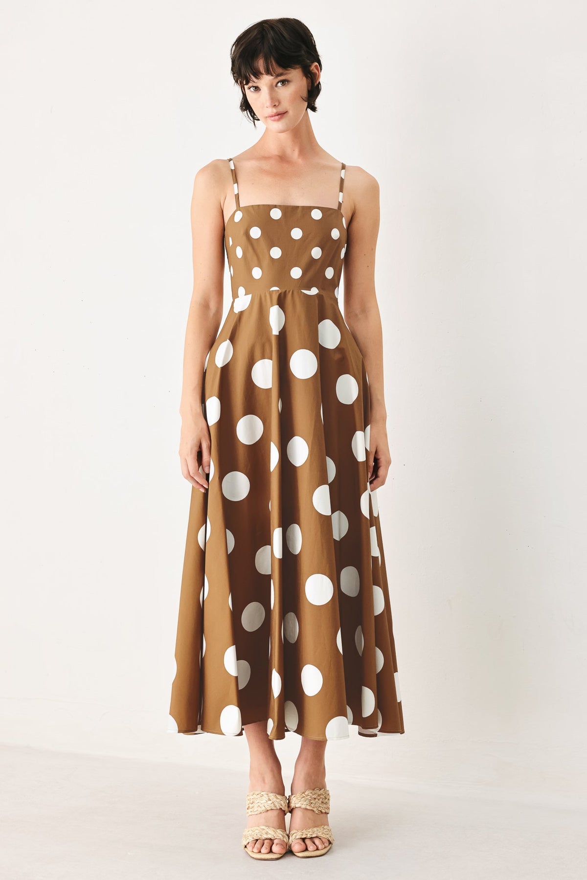 Woman wearing a brown dress with white polka dots on a white background