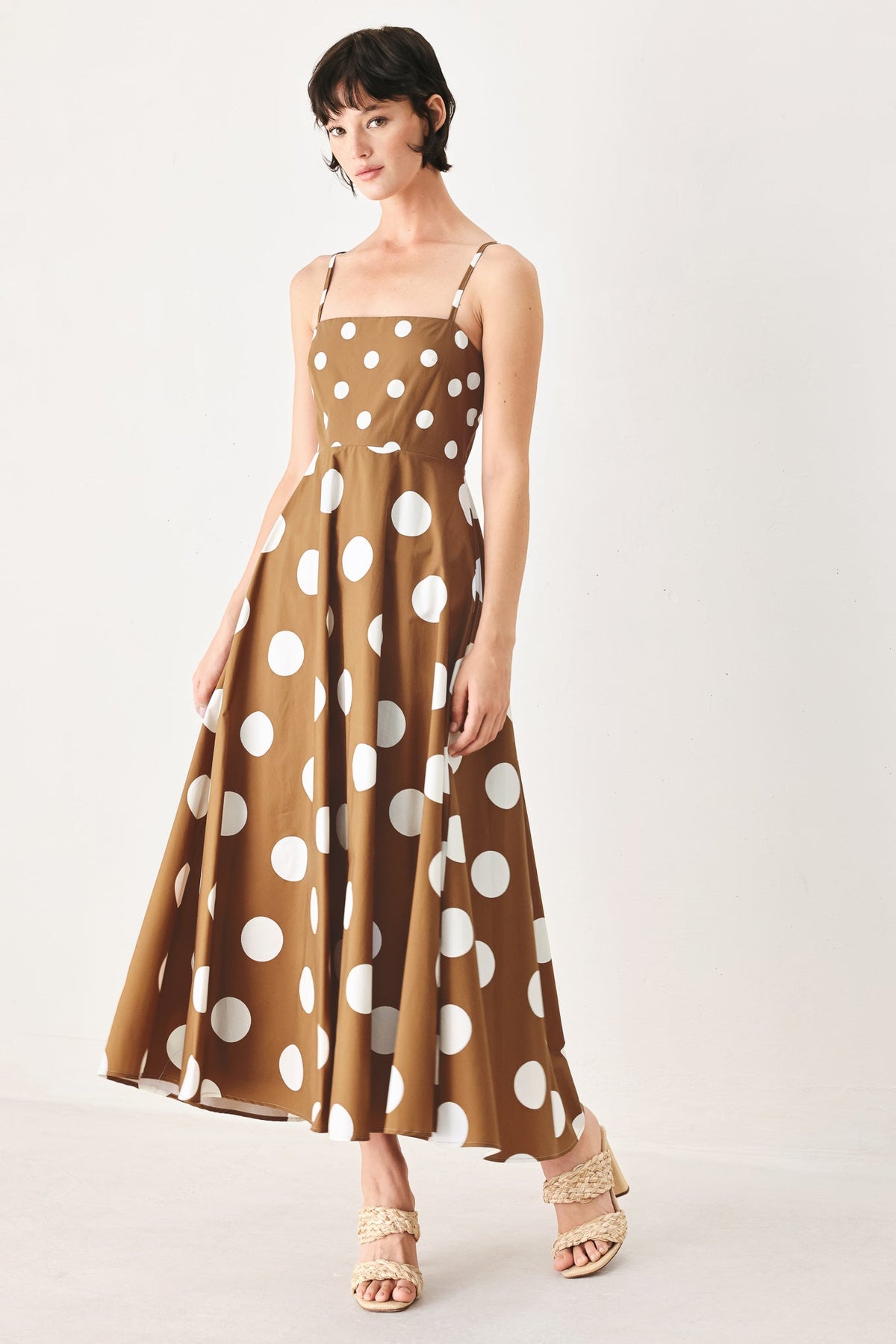 Woman wearing a brown dress with white polka dots on a white background