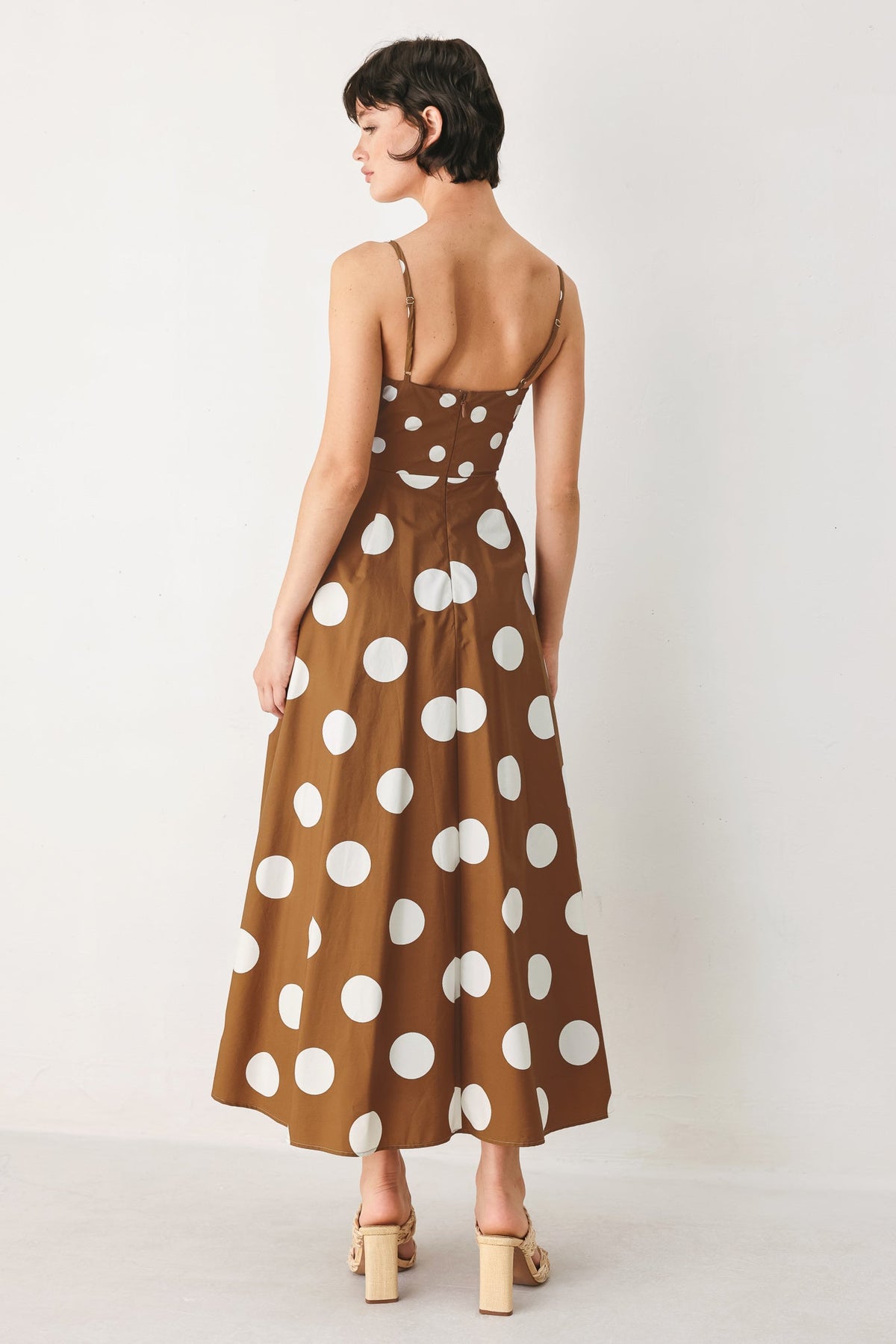 Woman wearing a brown dress with white polka dots on a white background