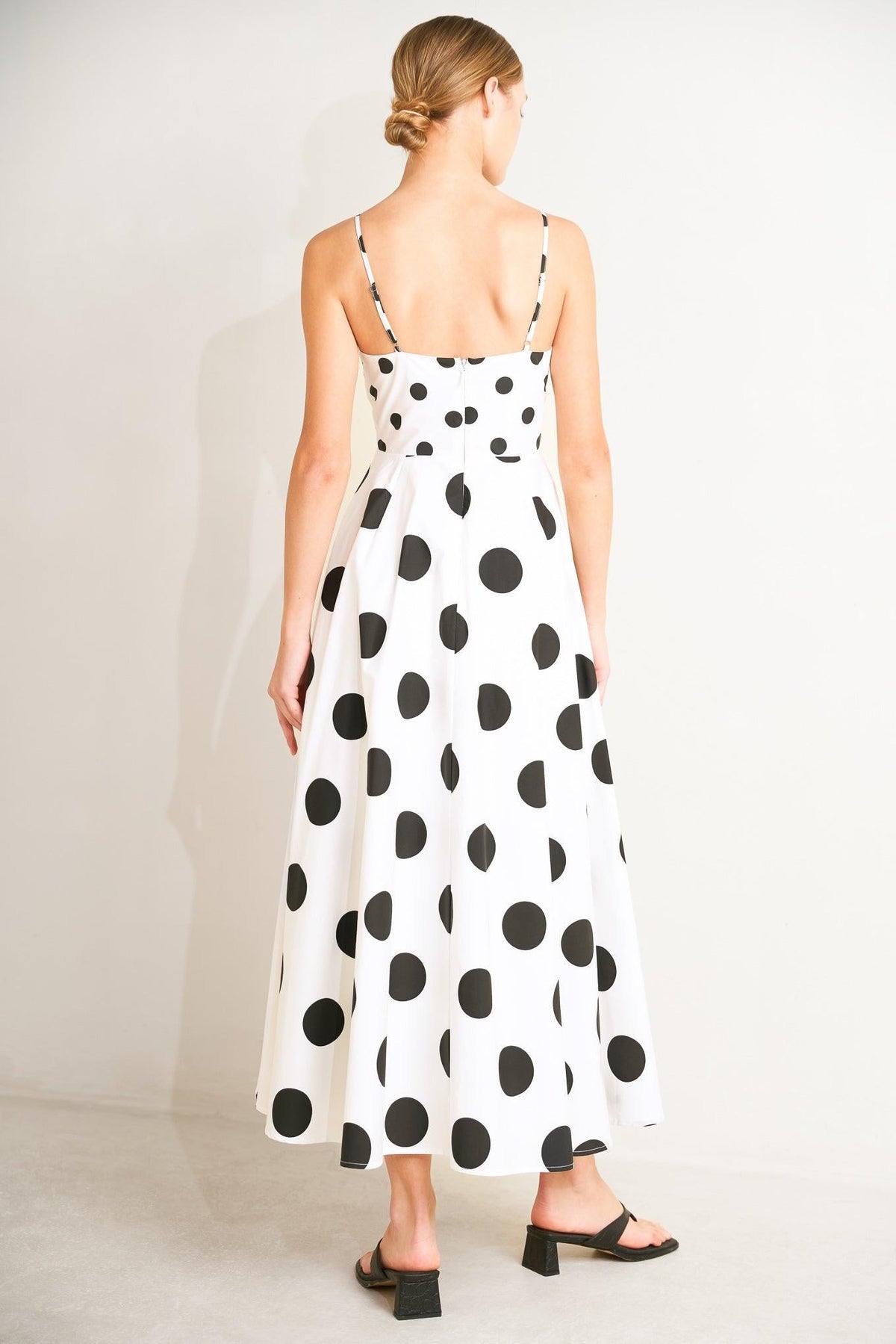 Woman wearing a polka dot dress on a plain background