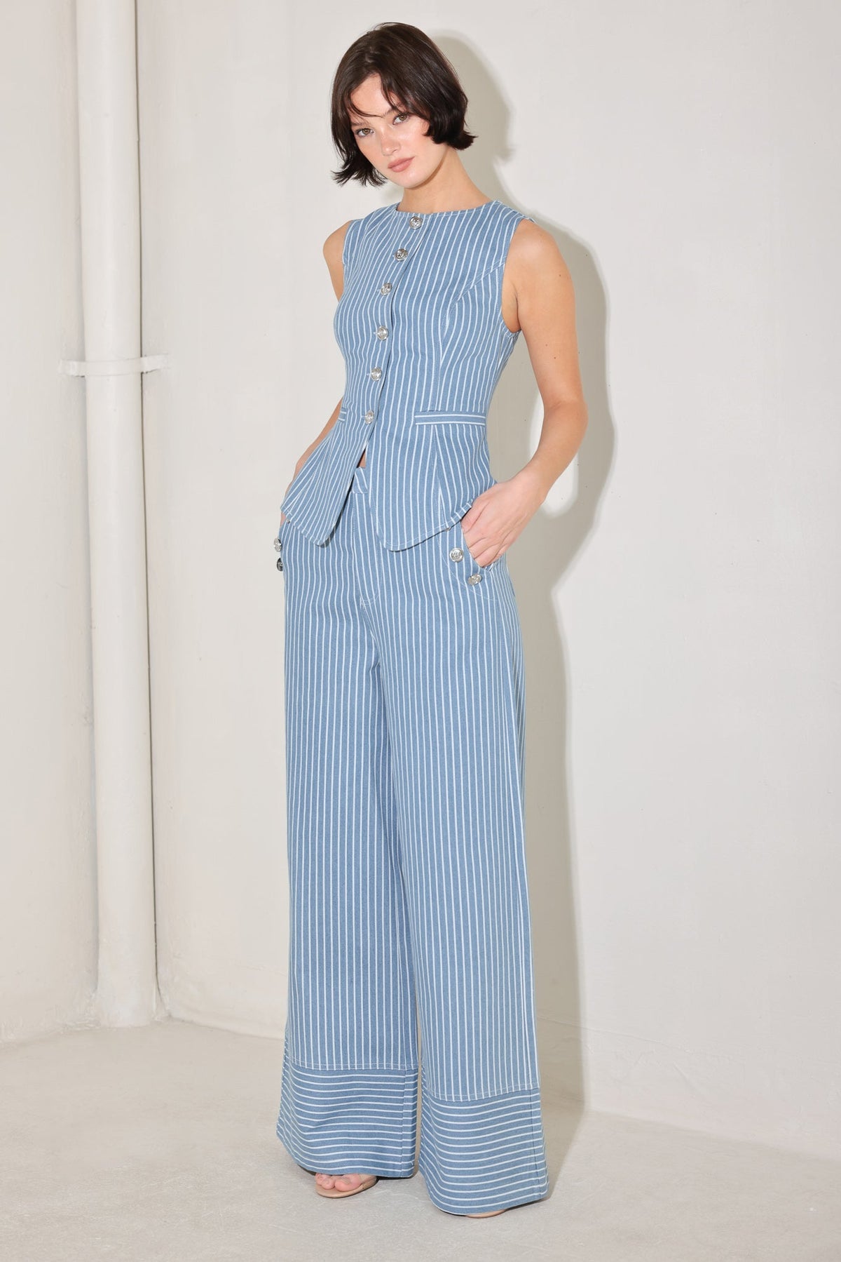 Woman wearing a blue striped jumpsuit against a white background