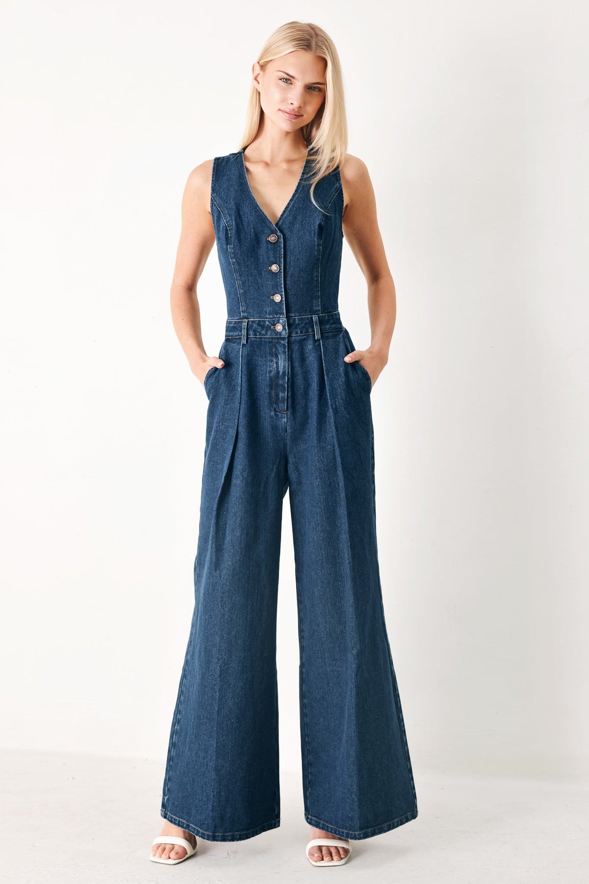 Woman wearing a blue denim jumpsuit on a white background
