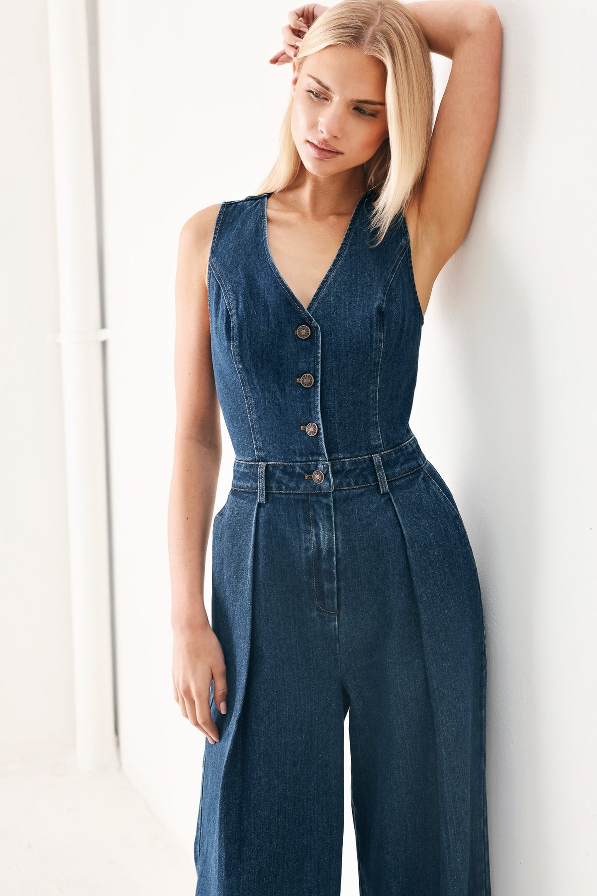 Woman wearing a denim jumpsuit against a white background