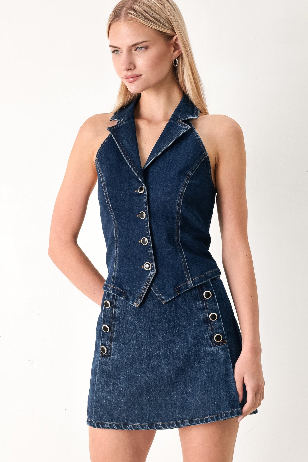 Woman wearing a denim dress with buttons on a white background