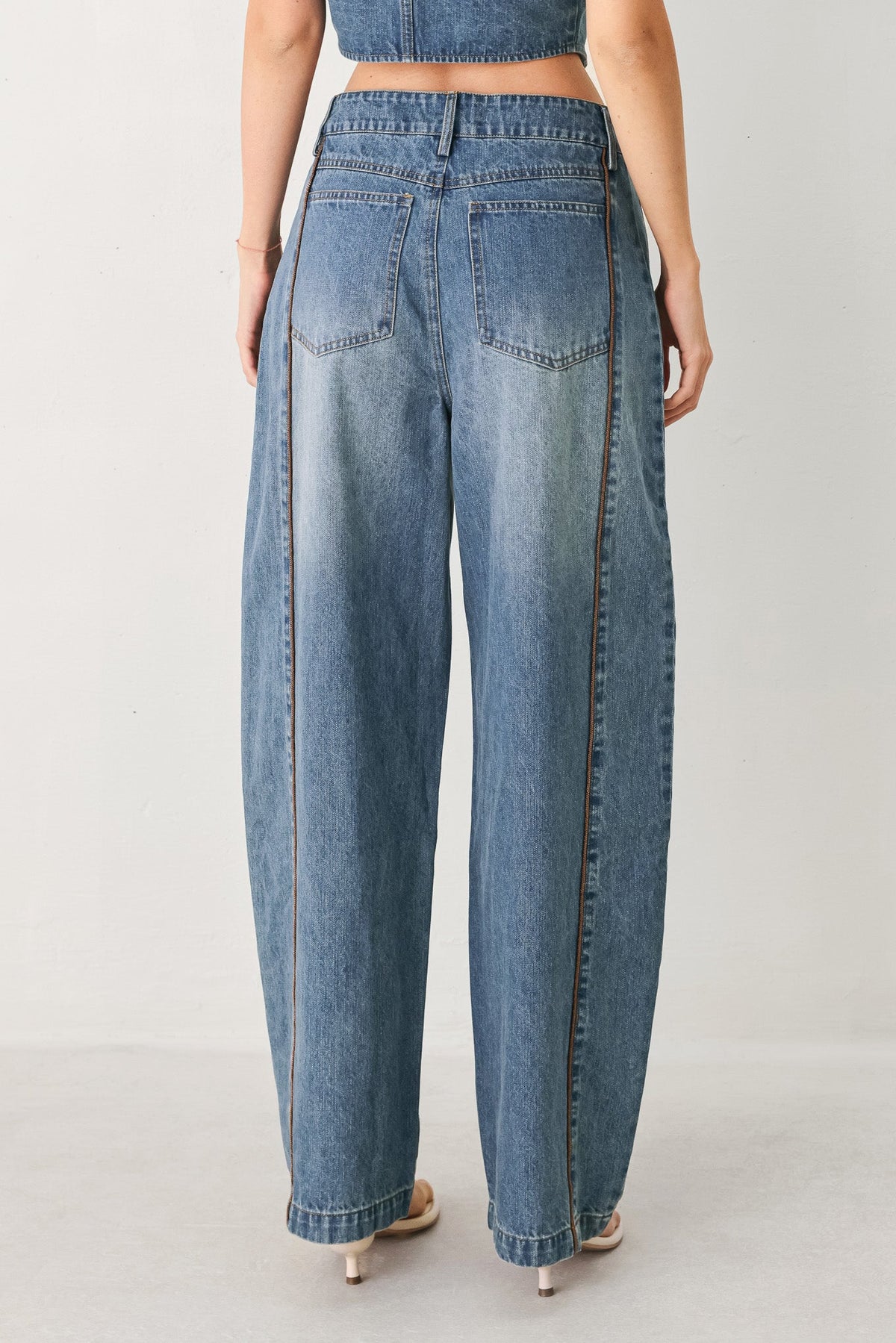 Person wearing blue jeans on a plain background