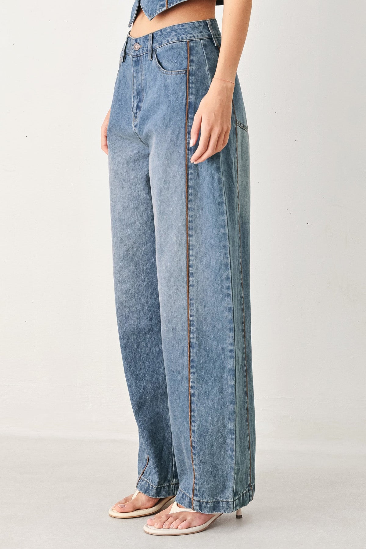 Person wearing light blue wide-leg jeans on a plain background