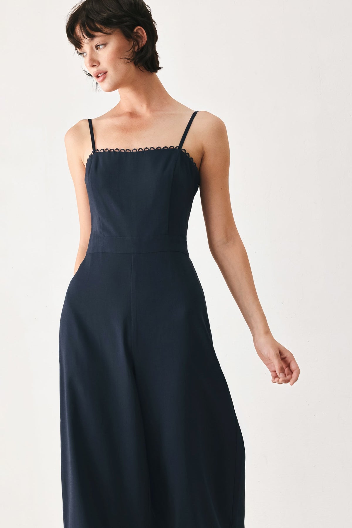 Woman wearing a navy blue dress with thin straps on a white background