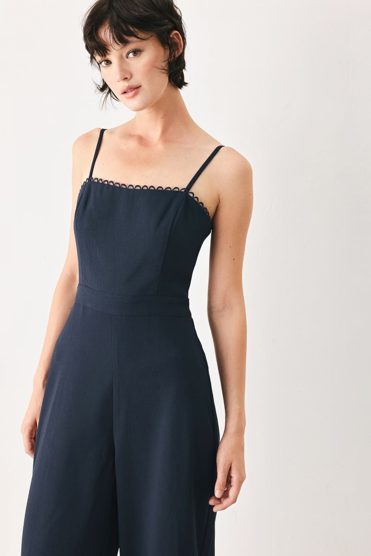 Woman wearing a navy blue dress with thin straps on a white background