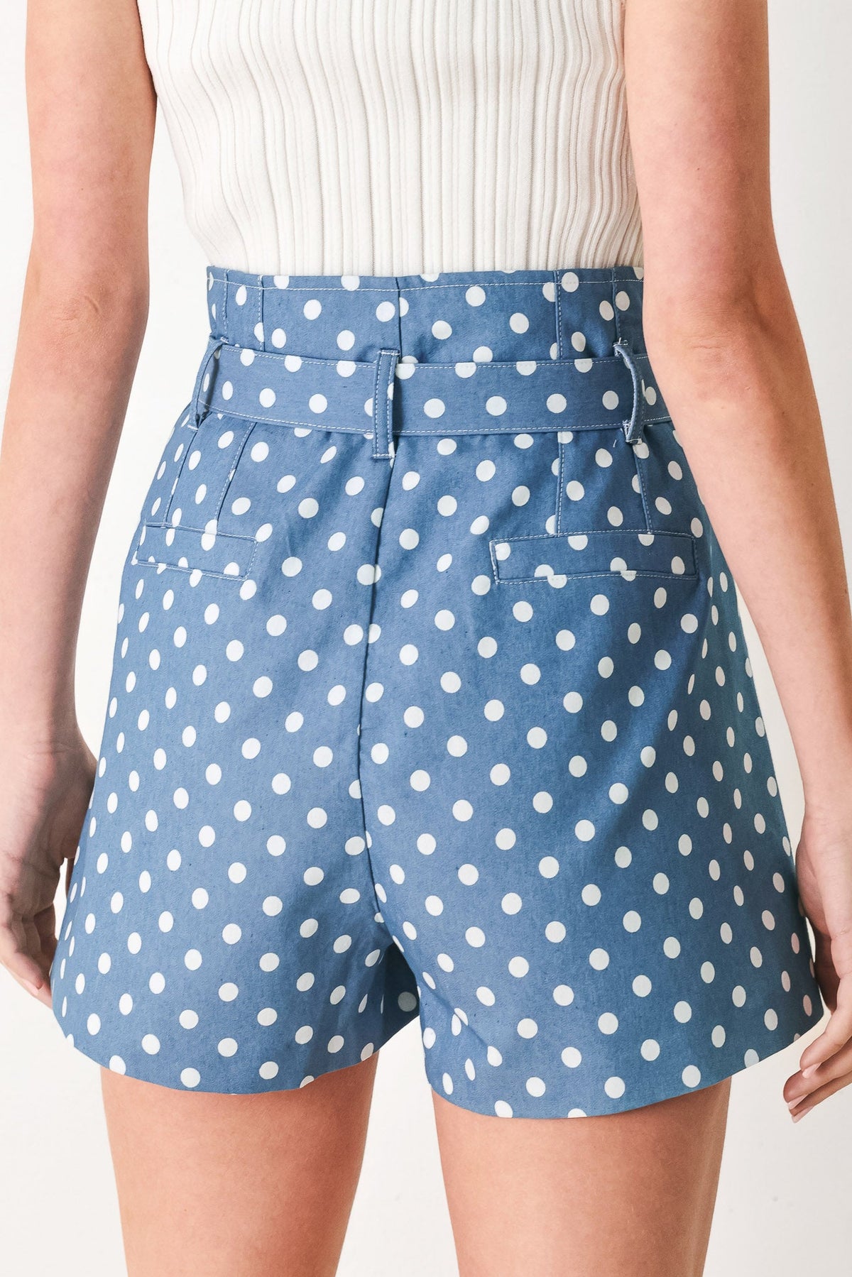 Blue polka dot shorts worn by a person on a plain background