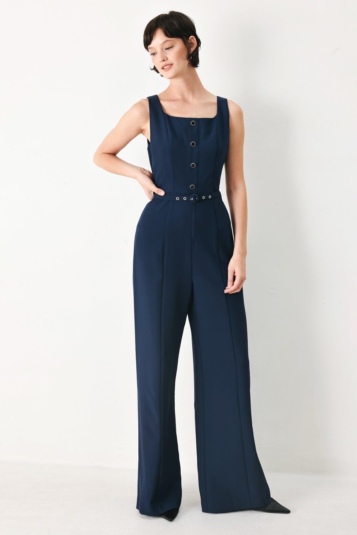Woman wearing a navy blue jumpsuit on a white background