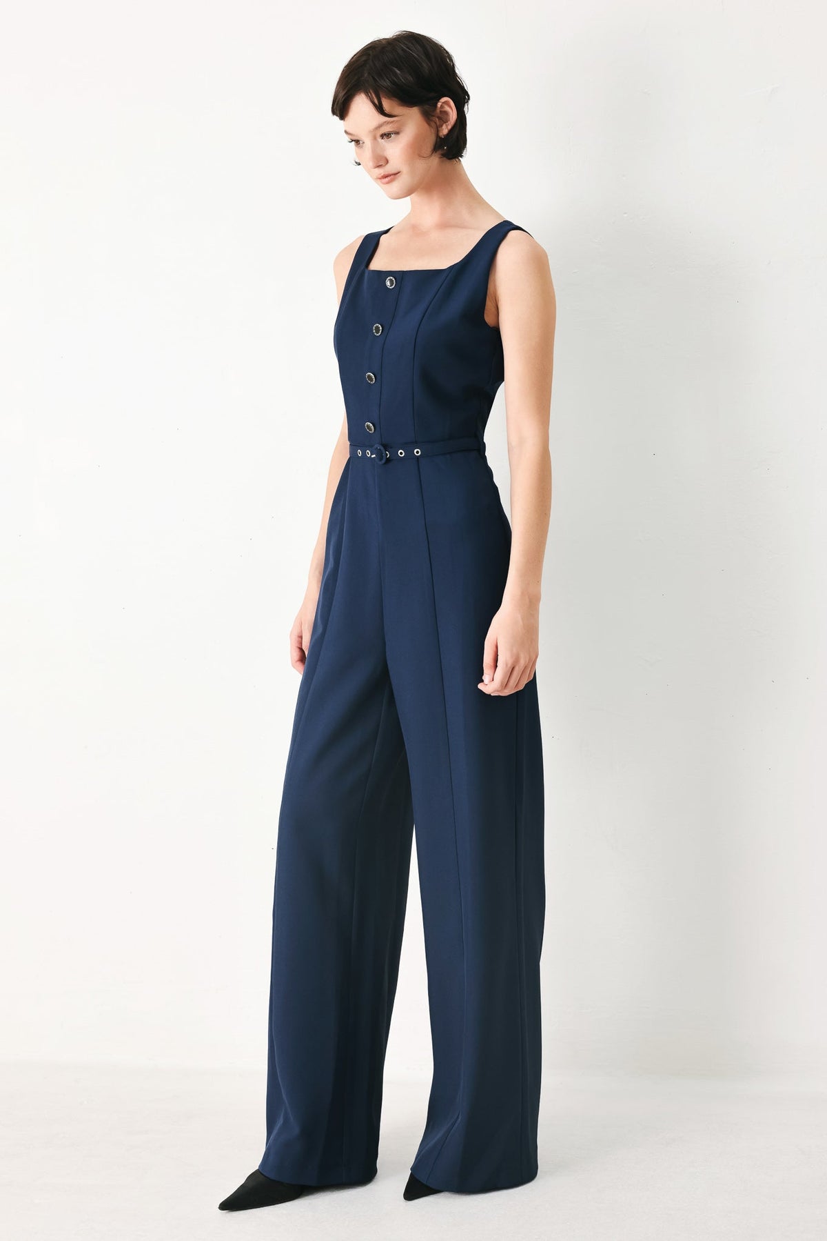 Woman wearing a navy blue jumpsuit on a white background