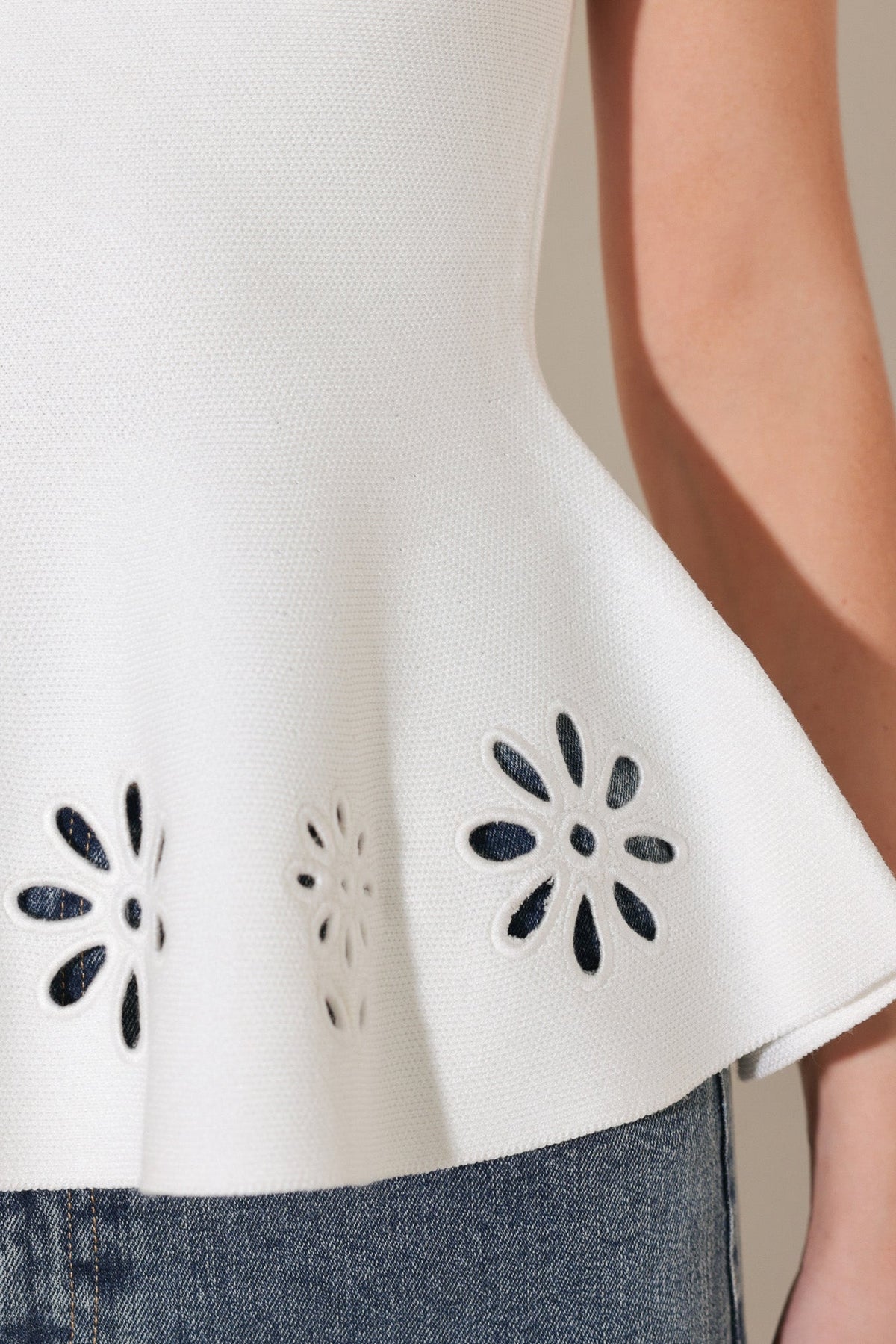 White top with black floral cut-out details on a neutral background