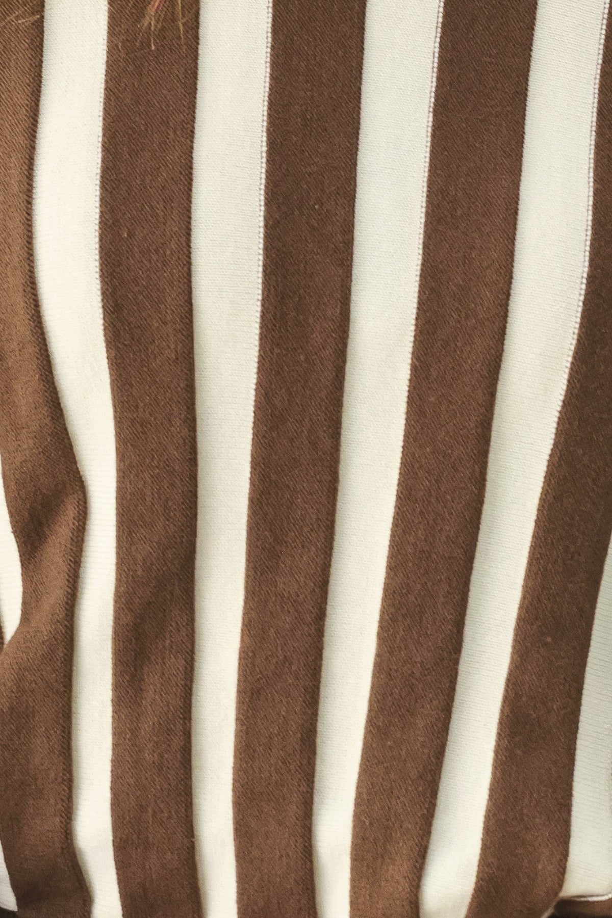 A close-up of a vertically striped fabric with alternating thick brown and off-white stripes.