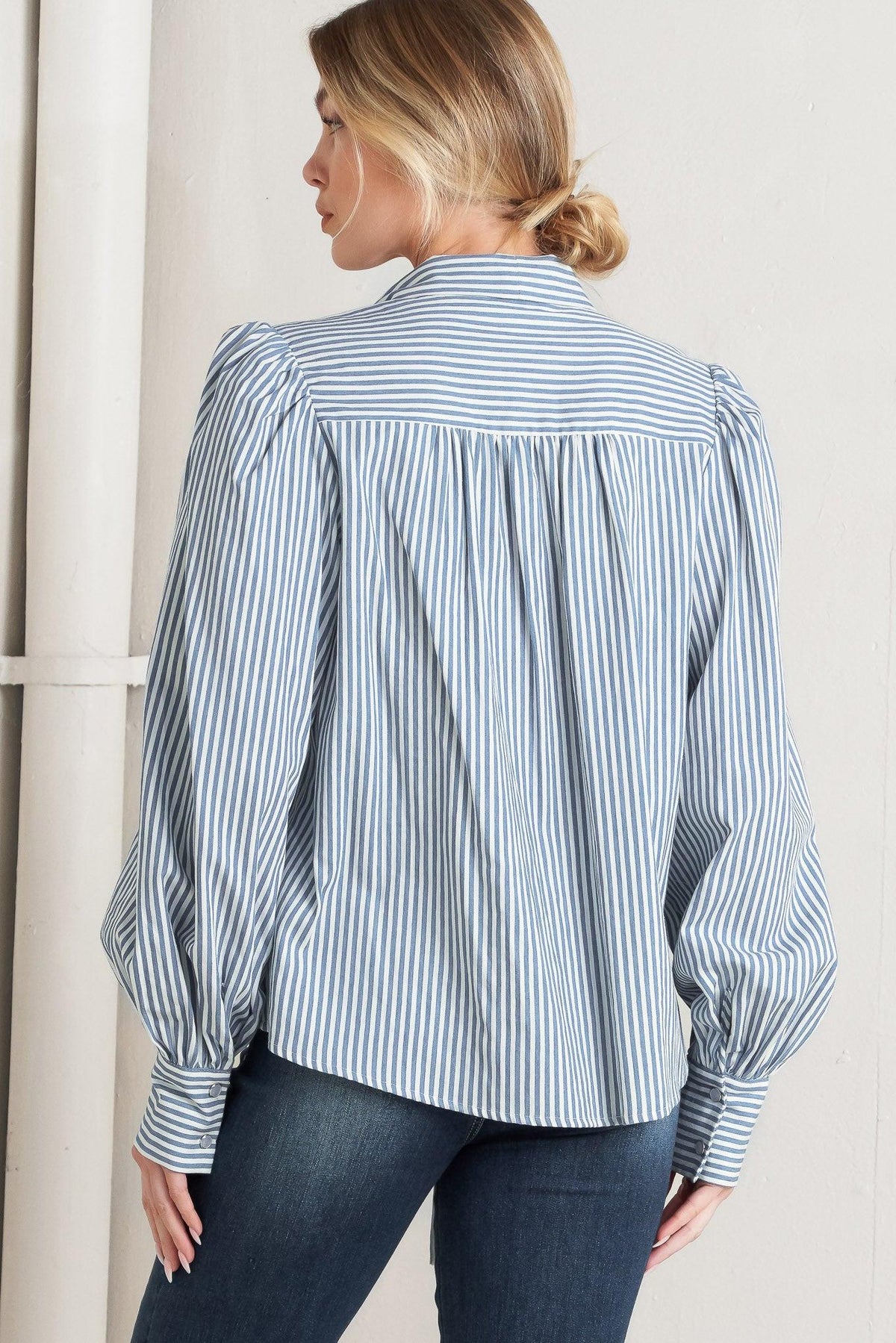 Woman wearing a blue and white striped shirt against a neutral background