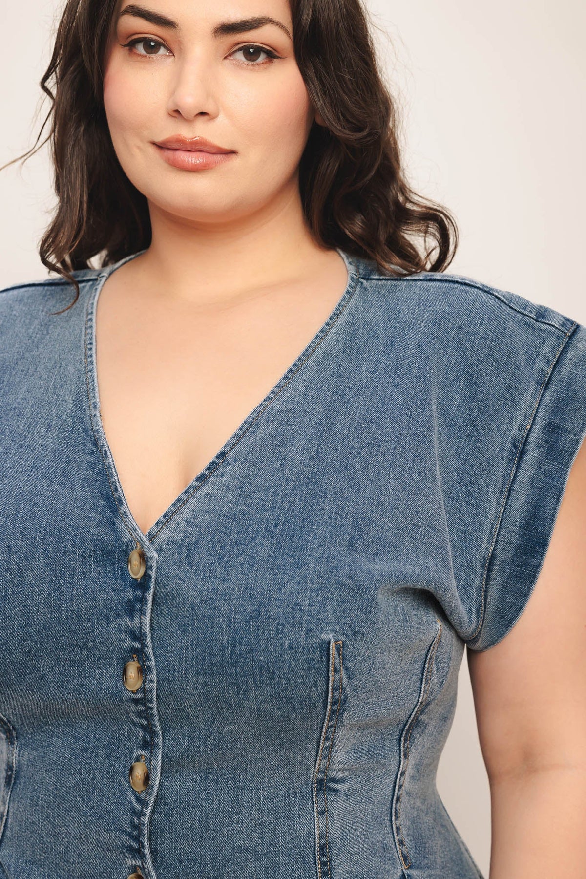 Woman wearing a denim dress with a plain background