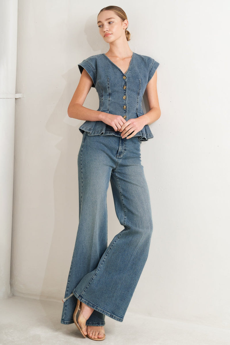 Woman wearing a denim outfit with a top and flared jeans against a white background