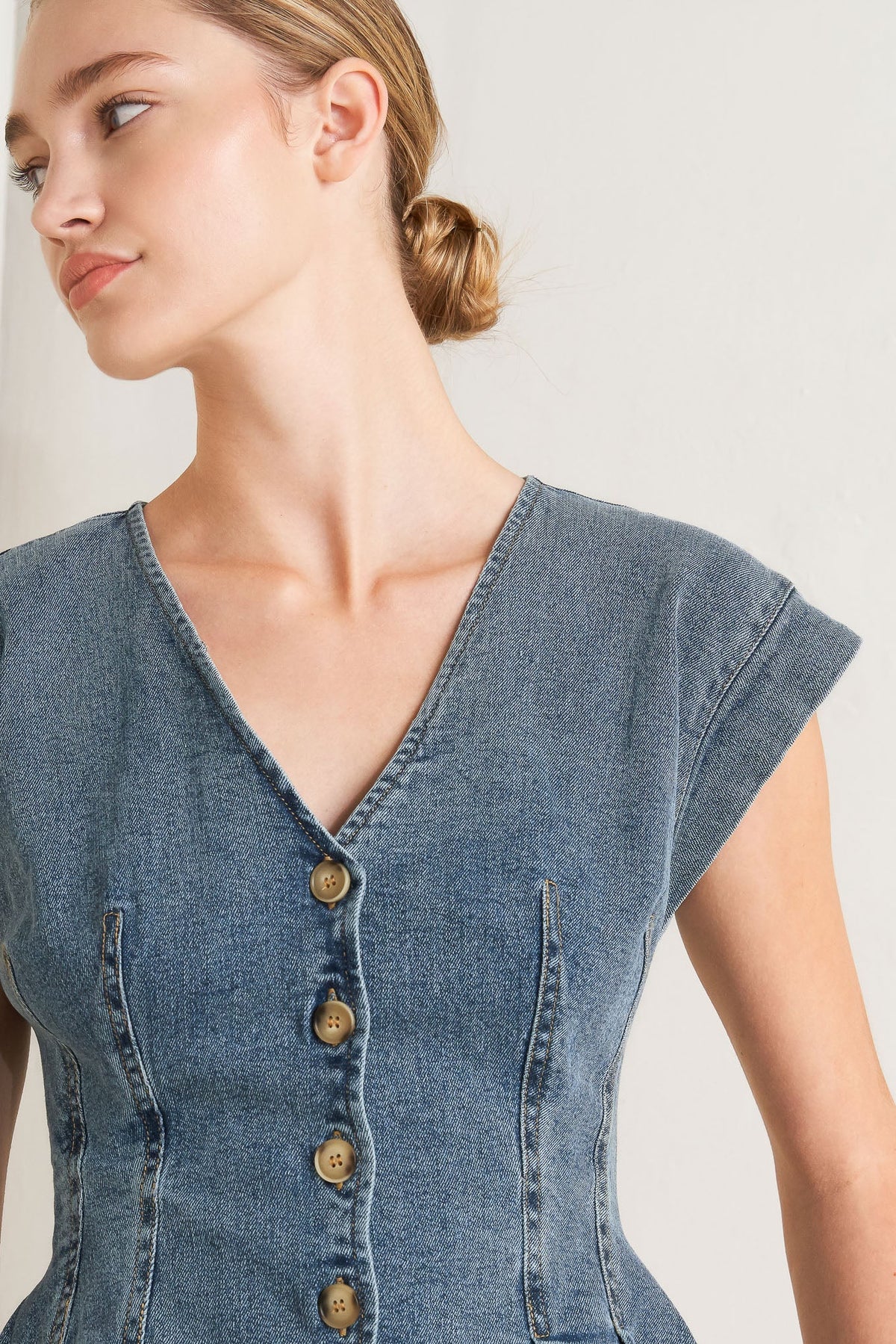 Woman wearing a denim dress with a plain background