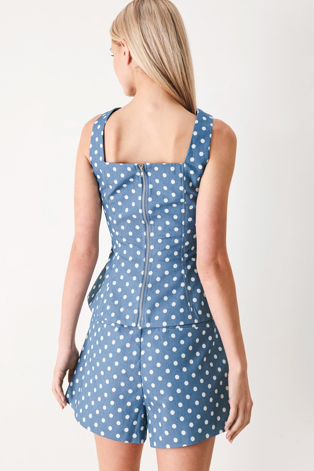 Woman wearing a blue polka dot romper on a white background