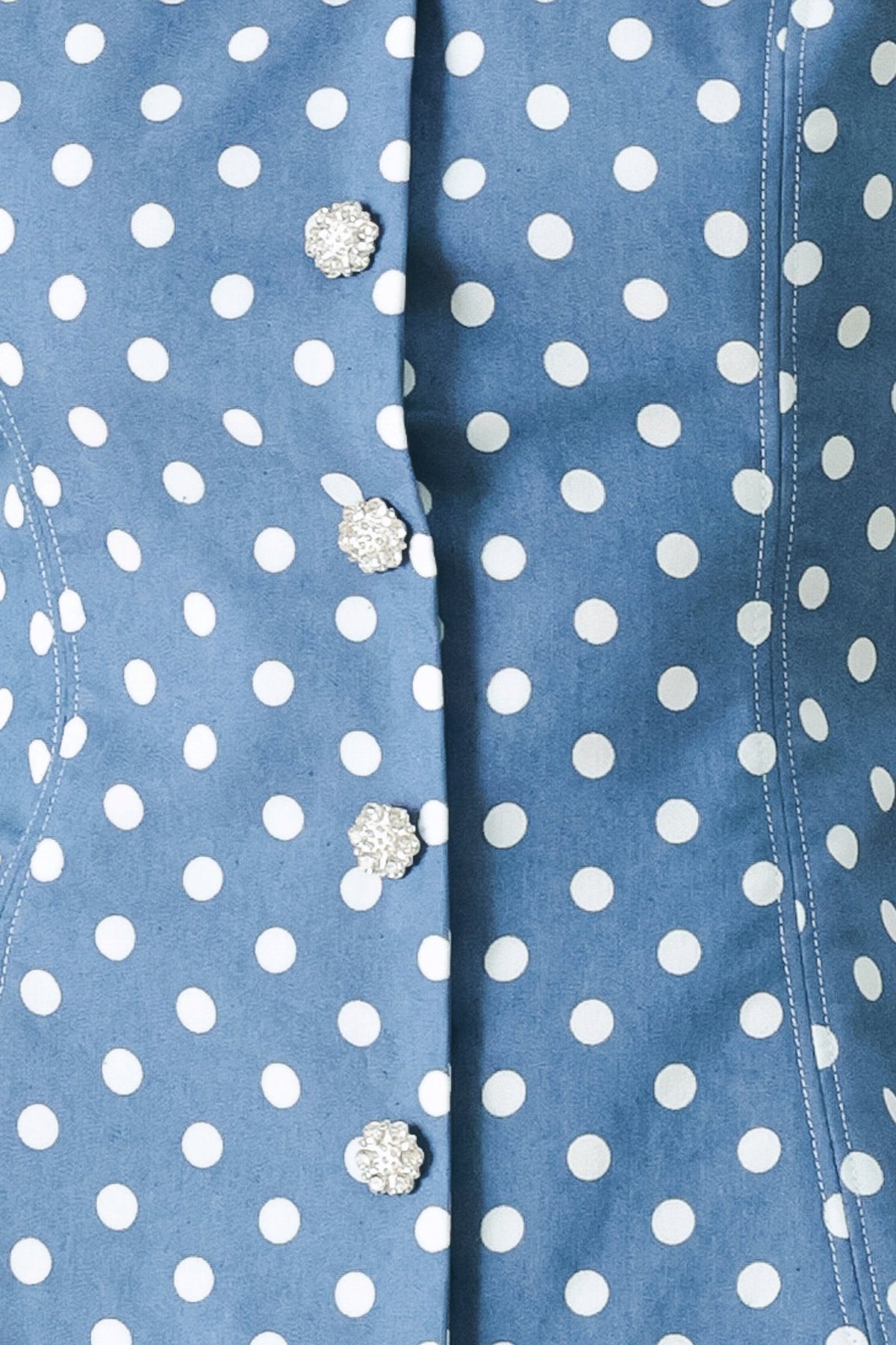 Close-up of a blue shirt with white polka dots and decorative buttons.